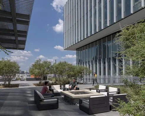 A patio with several couches and tables in front of a building.